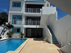 A multi-story building with a swimming pool, outdoor seating, and a staircase. - Stylish 2BR/2.5 BA Cancún Getaway with Pool, AC & Full Kitchen (Cancún)