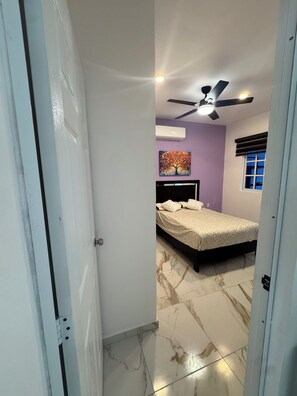 A bedroom with a bed, an air conditioner, a ceiling fan, and a window with blinds. - Stylish 2BR/2.5 BA Cancún Getaway with Pool, AC & Full Kitchen (Cancún)