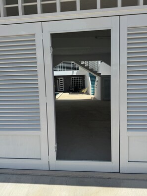 A building entrance with a garage door, a covered outdoor area with a table and chairs, and a staircase leading to an upper level. - Stylish 2BR/2.5 BA Cancún Getaway with Pool, AC & Full Kitchen (Cancún)