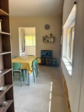 A dining area with a table and chairs, a television, and a clock on the wall. - SARACENA Realmonte, home to the Scala dei Turchi—a great destination for families and friends (Realmonte)