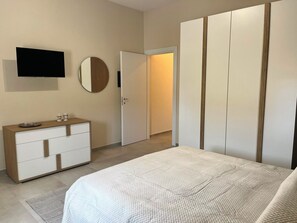 A bedroom with a bed, a dresser, a television, and a wardrobe. - SARACENA Realmonte, home to the Scala dei Turchi—a great destination for families and friends (Realmonte)