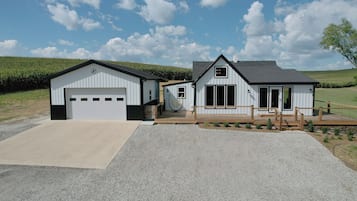 Un bâtiment à deux étages doté d’un garage, d’un porche couvert et d’une allée gravillonnée.