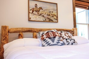 A bed with a wooden headboard, white bedding, and a patterned pillow.