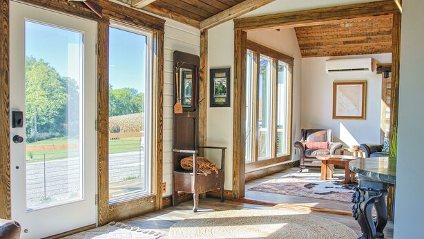 A room with large windows, a fireplace, and a dining area.
