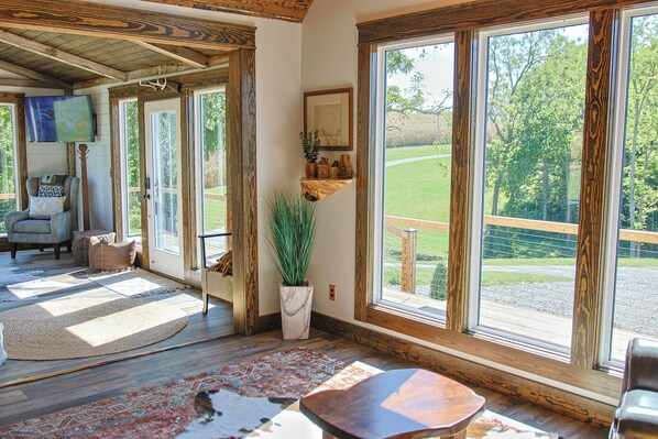 A spacious room with large windows, a wooden ceiling, and a cozy seating area with a rug and a plant. - Historic Weston Farmhouse - Private Countryside Escape (Weston)