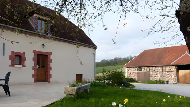 A building with a brick facade, a door, and a window. There is a grassy area with flowers and a bench. - Bed and Breakfast 'Chambre Amarante' with Shared Terrace, Wi-Fi and Air Conditioning (Maraye-en-Othe)