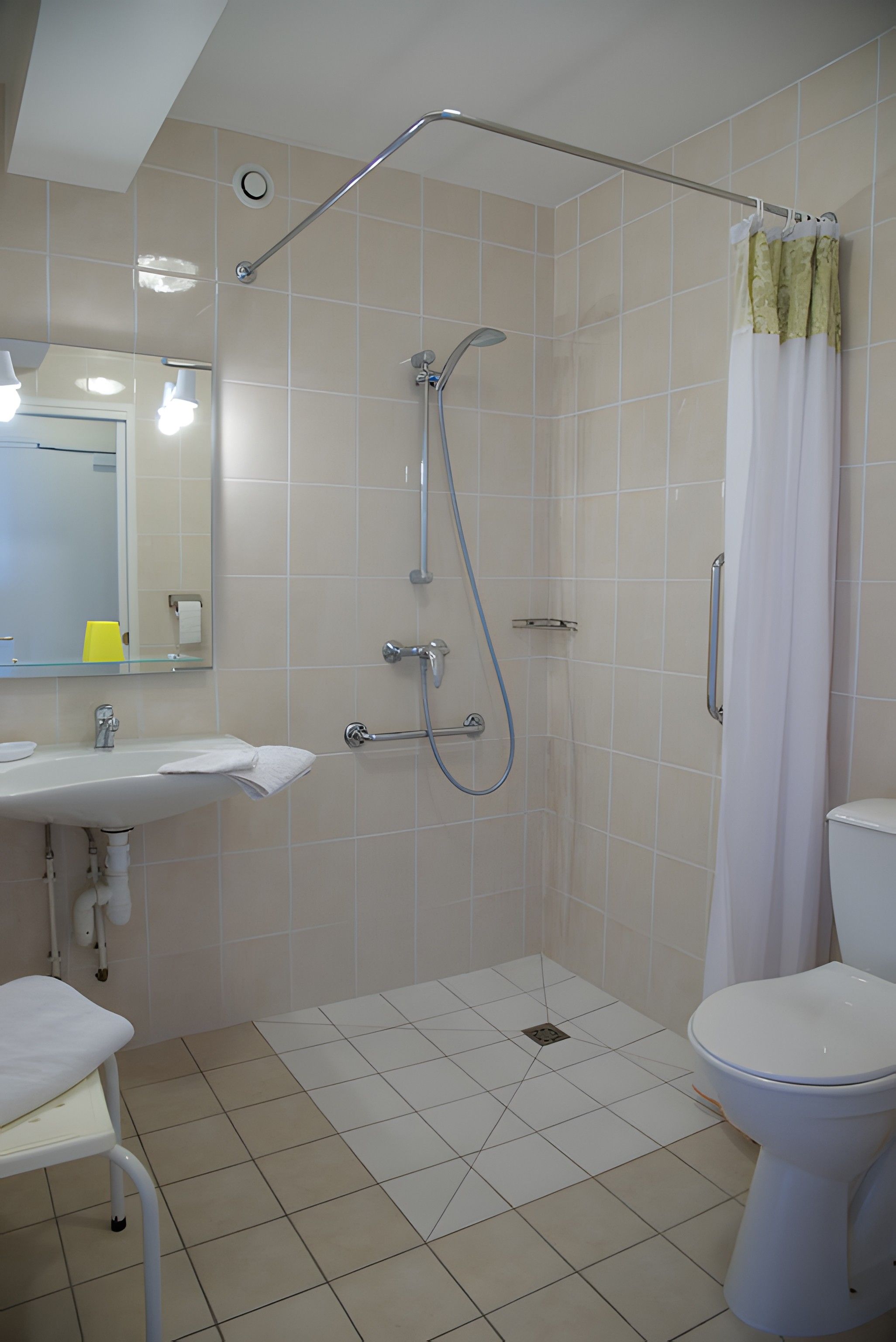 A bathroom with a shower, toilet, sink, and mirror.