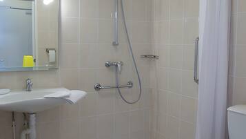 A bathroom with a shower, toilet, sink, and mirror.