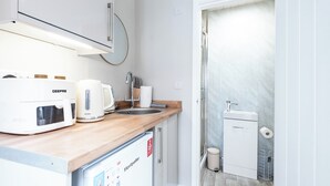 Una cocina compacta con una cafetera Breville, un lavamanos y un refrigerador pequeño.