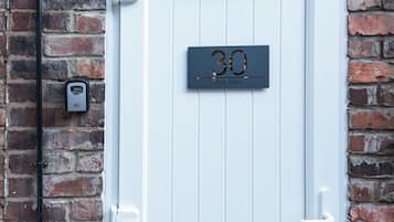 A white door with a number plate reading '30 The Wire' against a brick wall.
