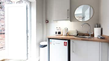 A compact kitchenette with a microwave, kettle, and sink.