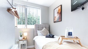 Un dormitorio moderno con cama, mesita de noche, lámpara y ventana con persianas.