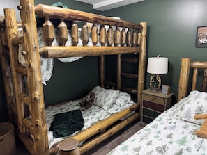 Una cama litera con una escalera de madera y una mesita de noche con una lámpara y un reloj.