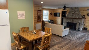 Un interior de cabaña acogedor con comedor, chimenea y sala de estar.
