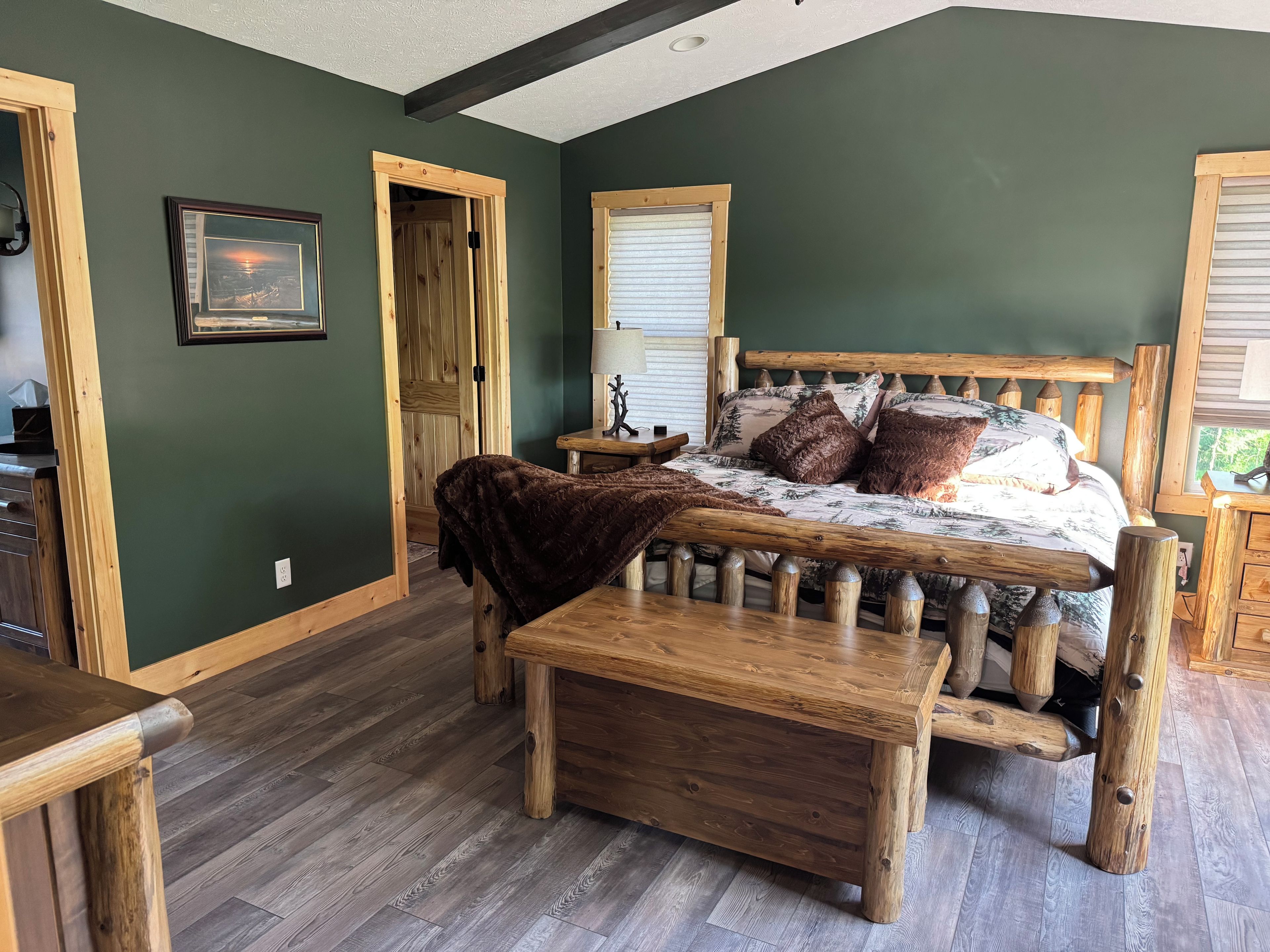 A rustic bedroom with a wooden bed, a bench, and a view of the outdoors.