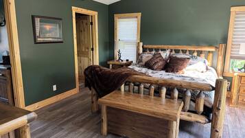 A rustic bedroom with a wooden bed, a bench, and a view of the outdoors.