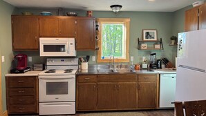 A kitchen with wooden cabinets, a microwave, stove, and a refrigerator.