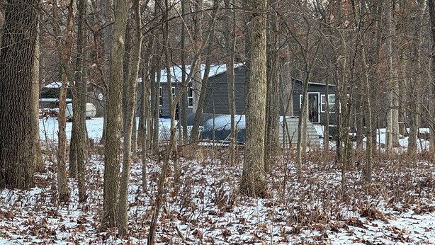 A cabin surrounded by a forest with snow on the ground.