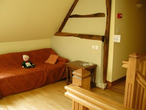 A cozy room with a wooden bench, a small table, and a sofa with a cushion.