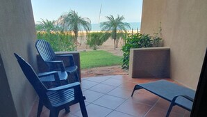 Un espacio al aire libre cubierto con vistas a la playa, que incluye una silla y una mesita.