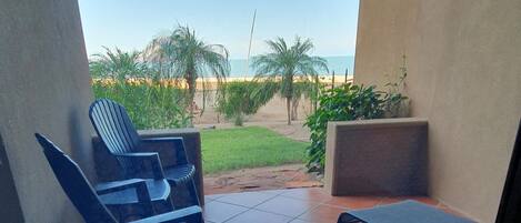 Ein überdachter Außenbereich mit Blick auf den Strand, inklusive Stuhl und kleinem Tisch.