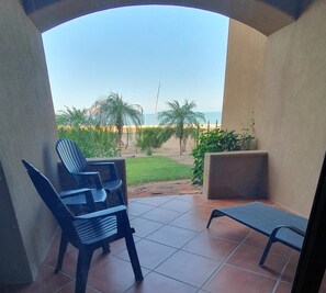 Un espace extérieur abrité avec vue sur la plage, comprenant une chaise et une petite table.