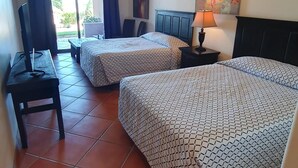Habitación de hotel con dos camas, un escritorio, un televisor y un cuadro en la pared.