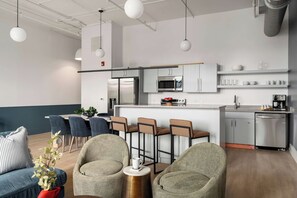 Een moderne keuken met barkrukken, een eettafel en een zithoek met banken en stoelen.