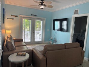 Ein Wohnzimmer mit Deckenventilator, Wandfernseher und einer Couch.