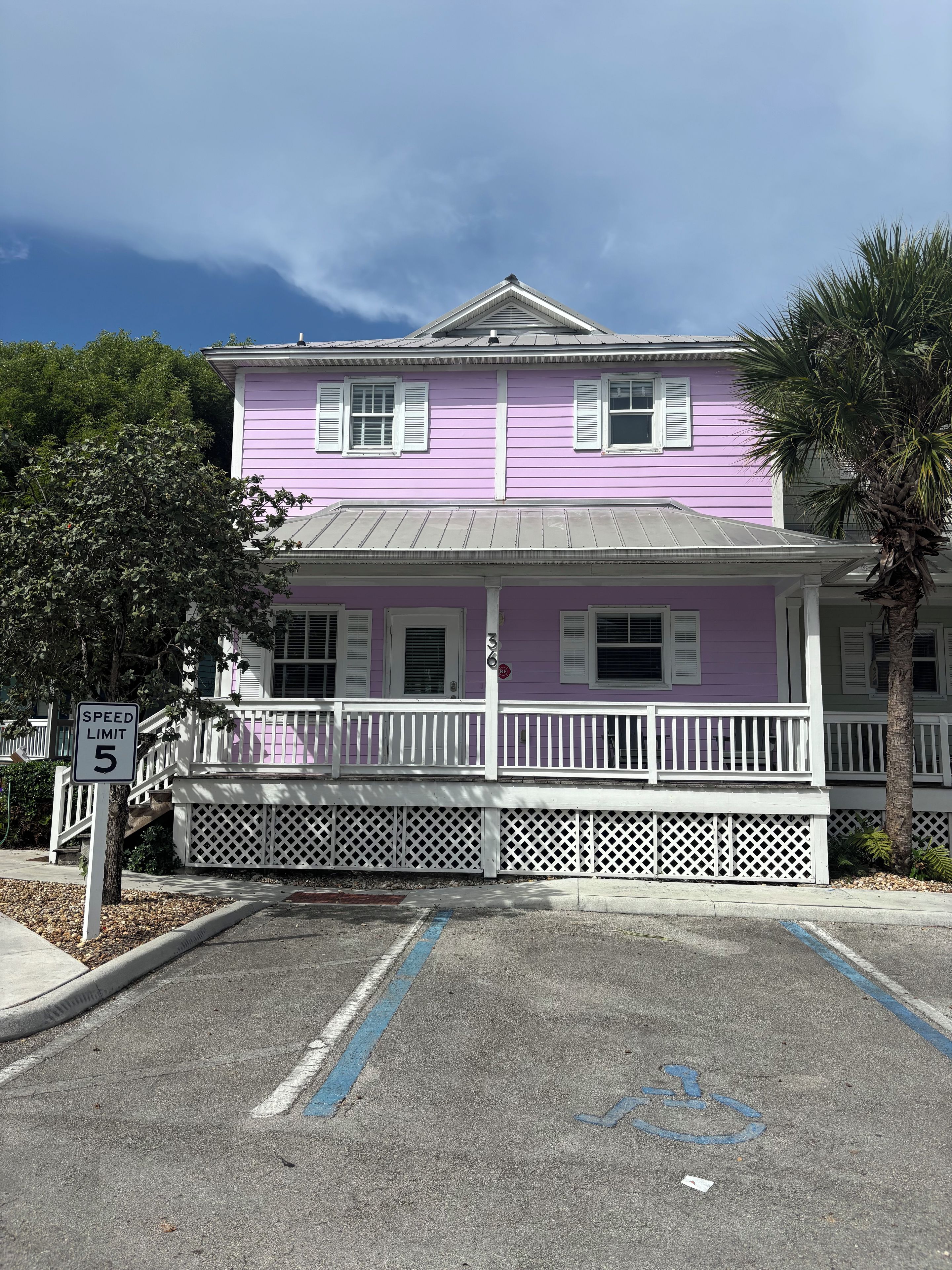 A two-story building with a white porch and a speed limit sign of 5.