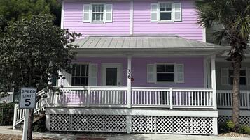 A two-story building with a white porch and a speed limit sign of 5.