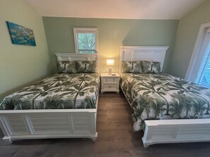 Una camera da letto con due letti, un comodino, una lampada e una finestra.