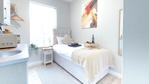 Een slaapkamer met een bed, nachtkastje en een raam.