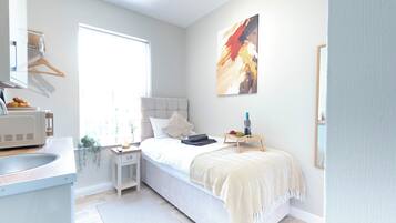 Une chambre à coucher avec un lit, une table de chevet et une fenêtre.
