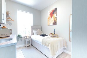 Une chambre à coucher avec un lit, une table de chevet et une fenêtre.