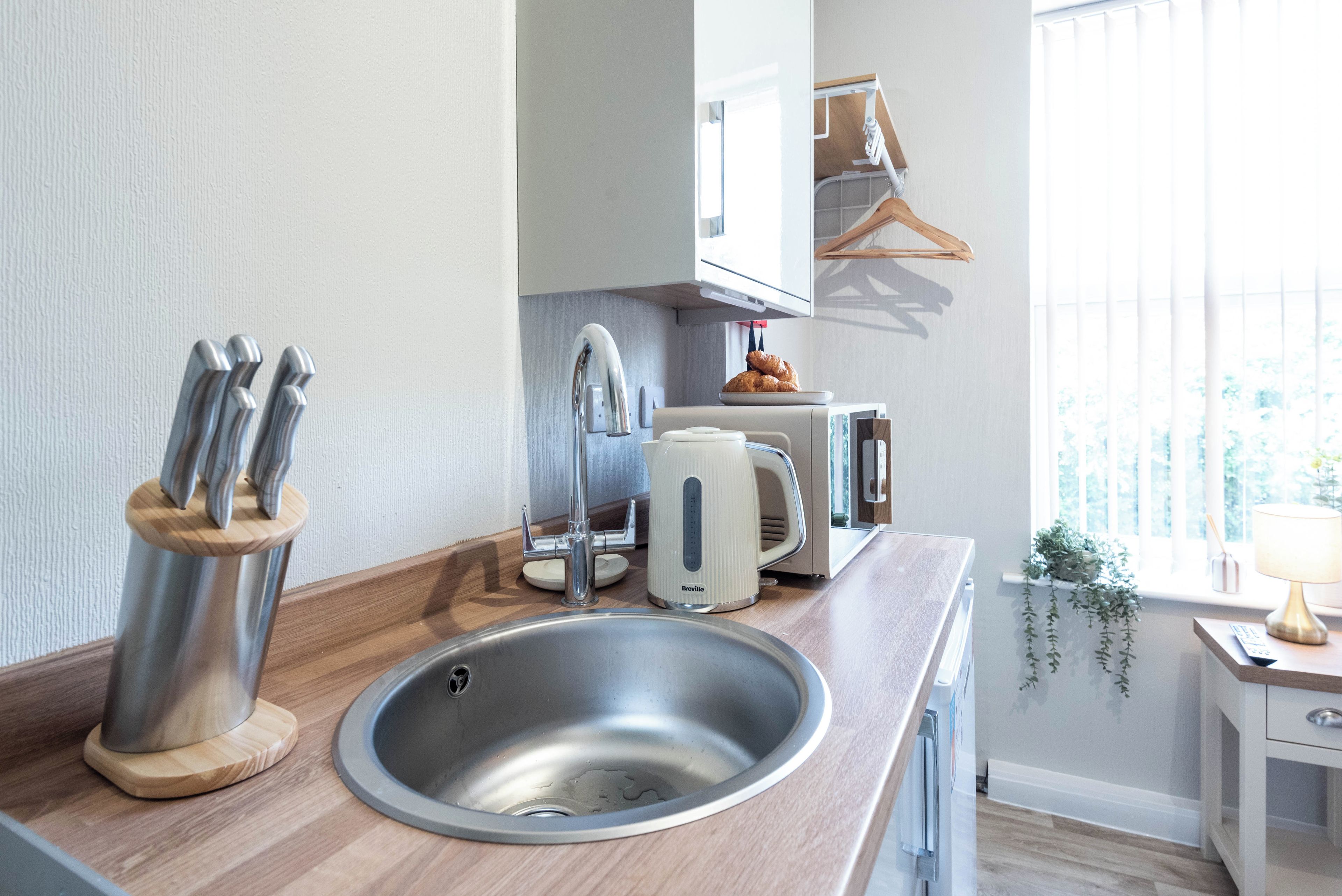 A modern kitchen with a stainless steel sink, a Breville toaster, and a knife block.