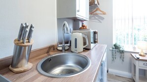 Een moderne keuken met een roestvrijstalen spoelbak, een Breville toaster en een messenblok.