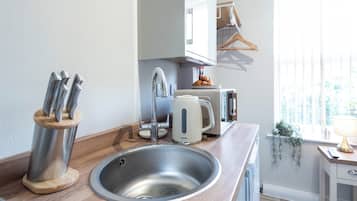 A modern kitchen with a stainless steel sink, a Breville toaster, and a knife block.