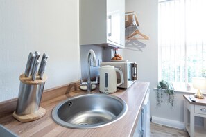 Une cuisine moderne dotée d’un évier en acier inoxydable, d’un grille-pain Breville et d’un bloc à couteaux.