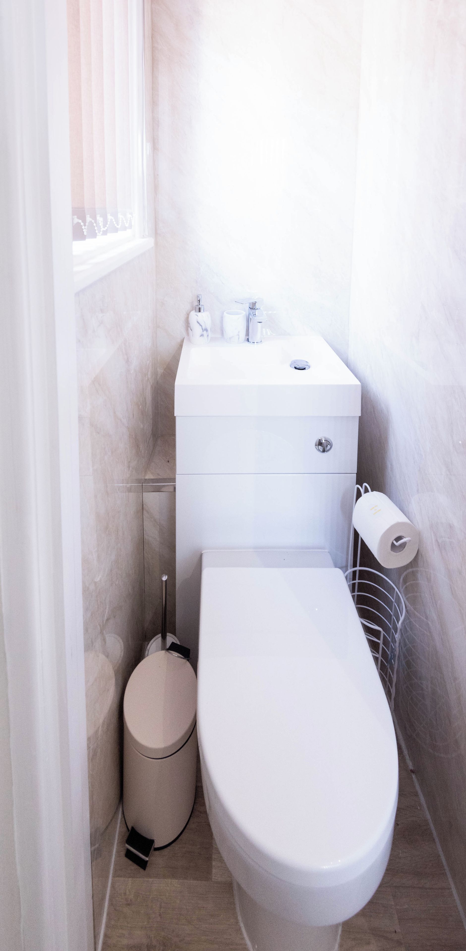 Une petite salle de bain moderne équipée de toilettes, d’un bidet et d’un porte-rouleau de papier toilette.