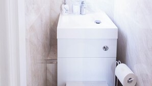 Een compacte, moderne badkamer met toilet, bidet en toiletrolhouder.