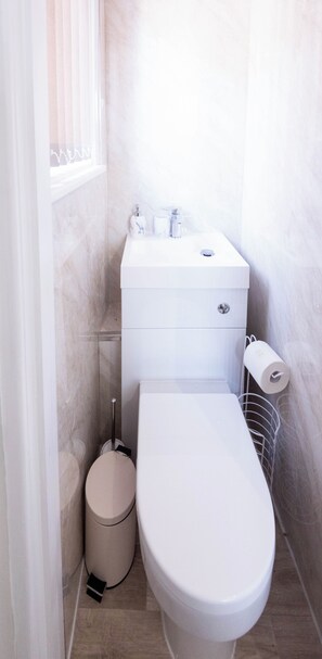 Une petite salle de bain moderne équipée de toilettes, d’un bidet et d’un porte-rouleau de papier toilette.