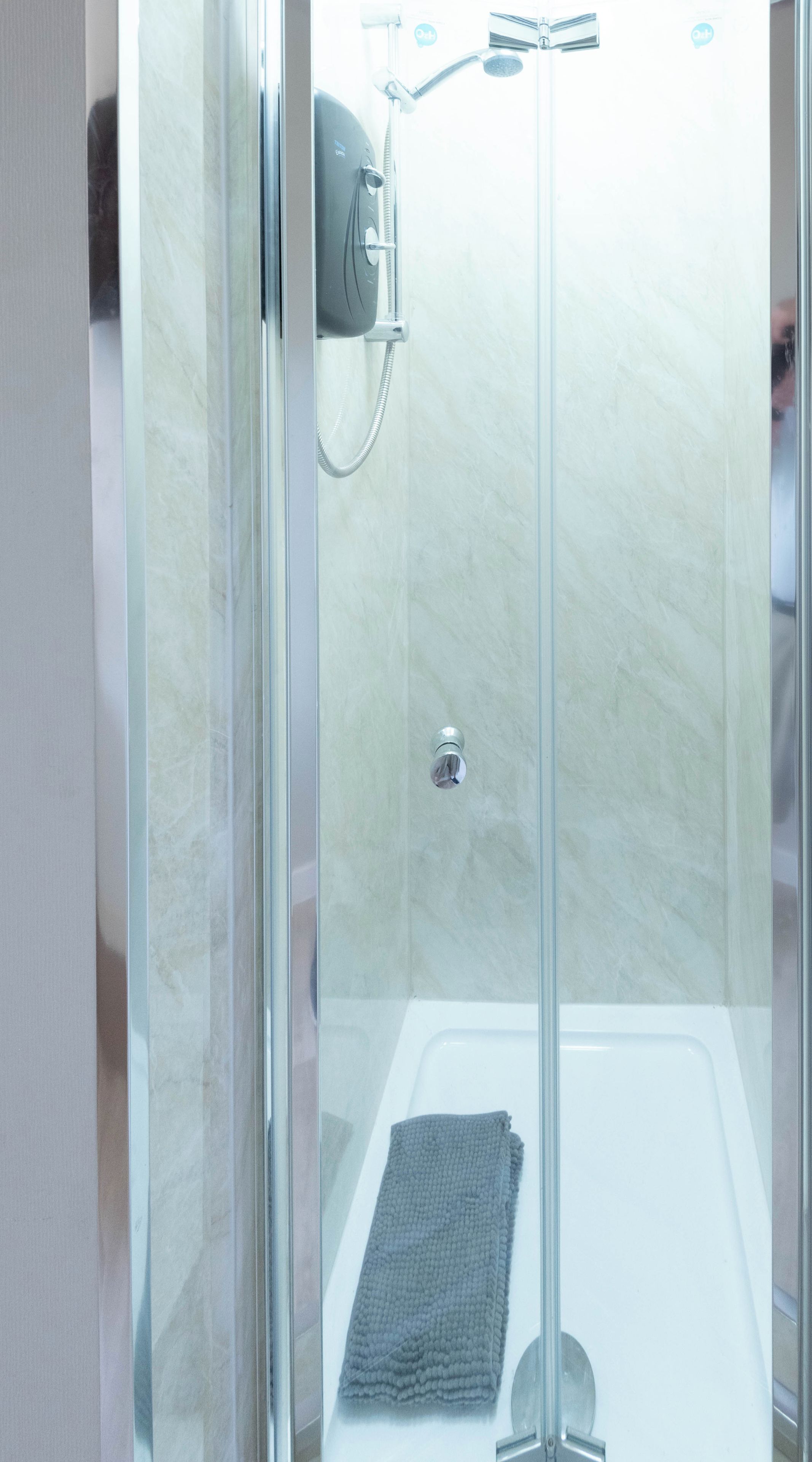 A glass-enclosed shower stall with a handheld showerhead and a handheld shower attachment.