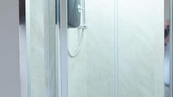 A glass-enclosed shower stall with a handheld showerhead and a handheld shower attachment.
