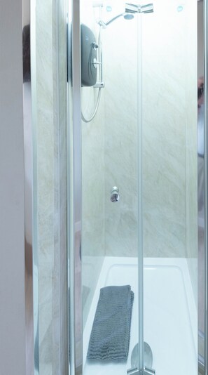 Een douchecabine met glazen wanden, een handdouche en een extra douchekop.