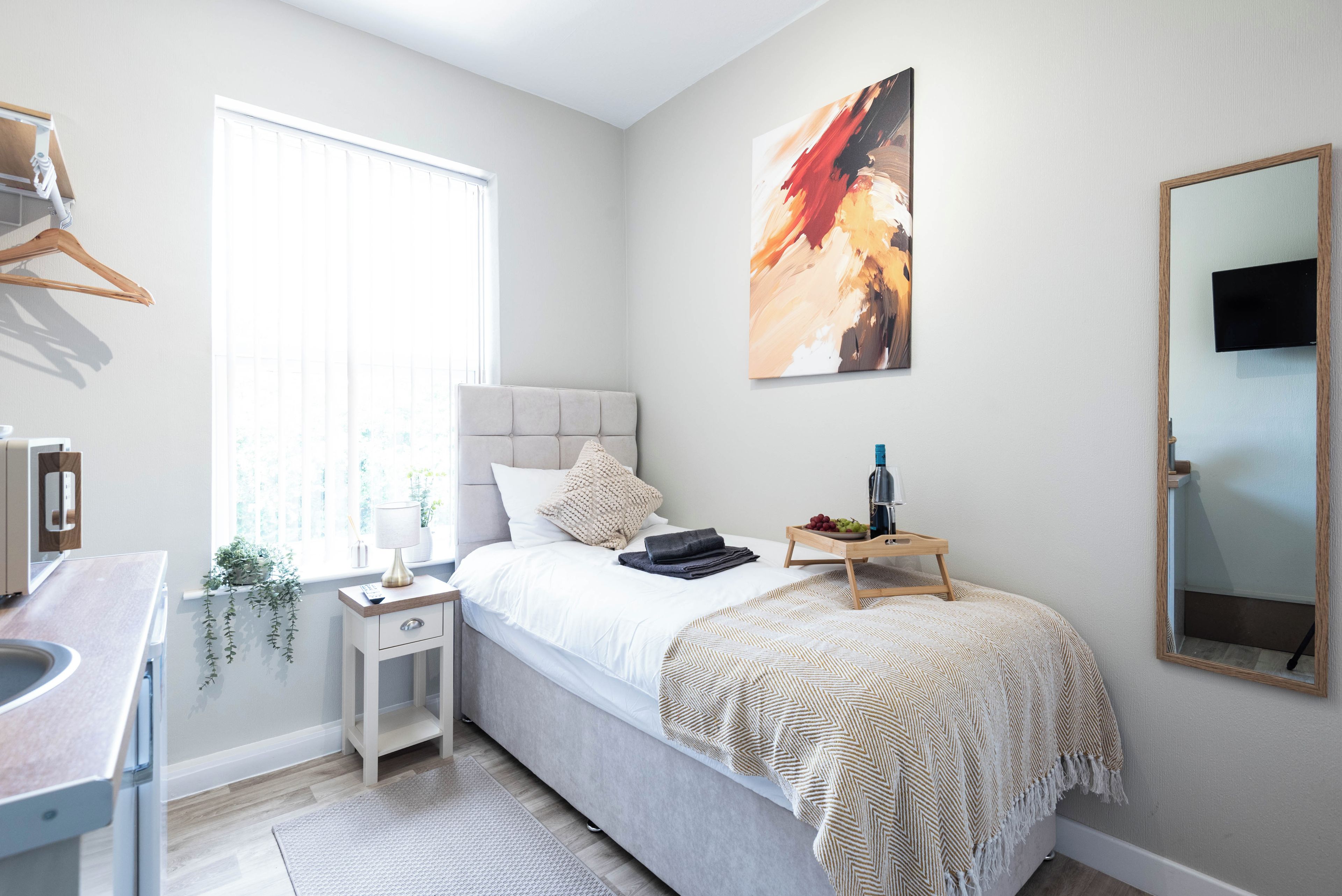 A bedroom with a bed, bedside table, lamp, and a painting on the wall.