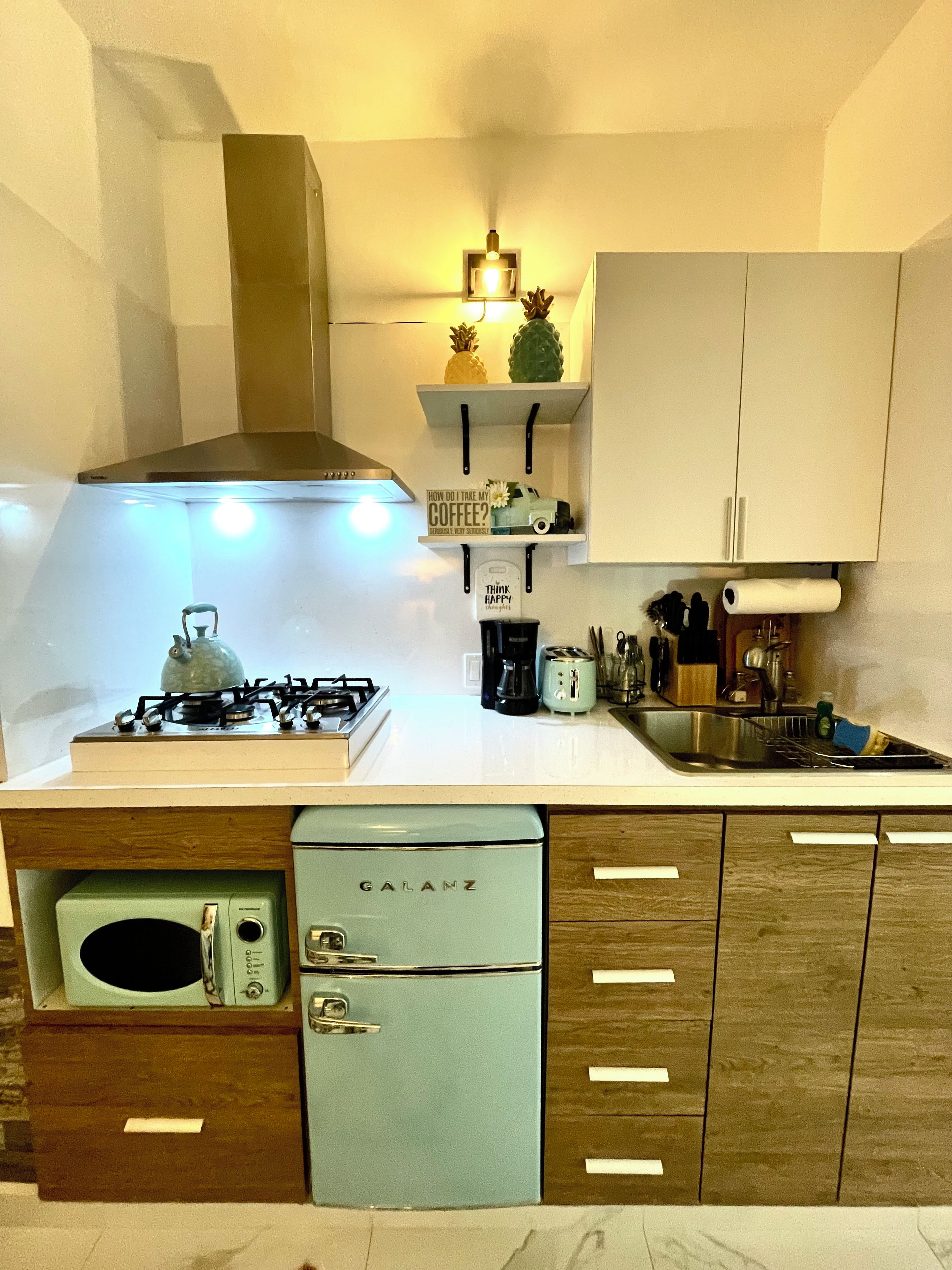 A compact kitchen with a gas stove, a coffee maker, and a refrigerator.