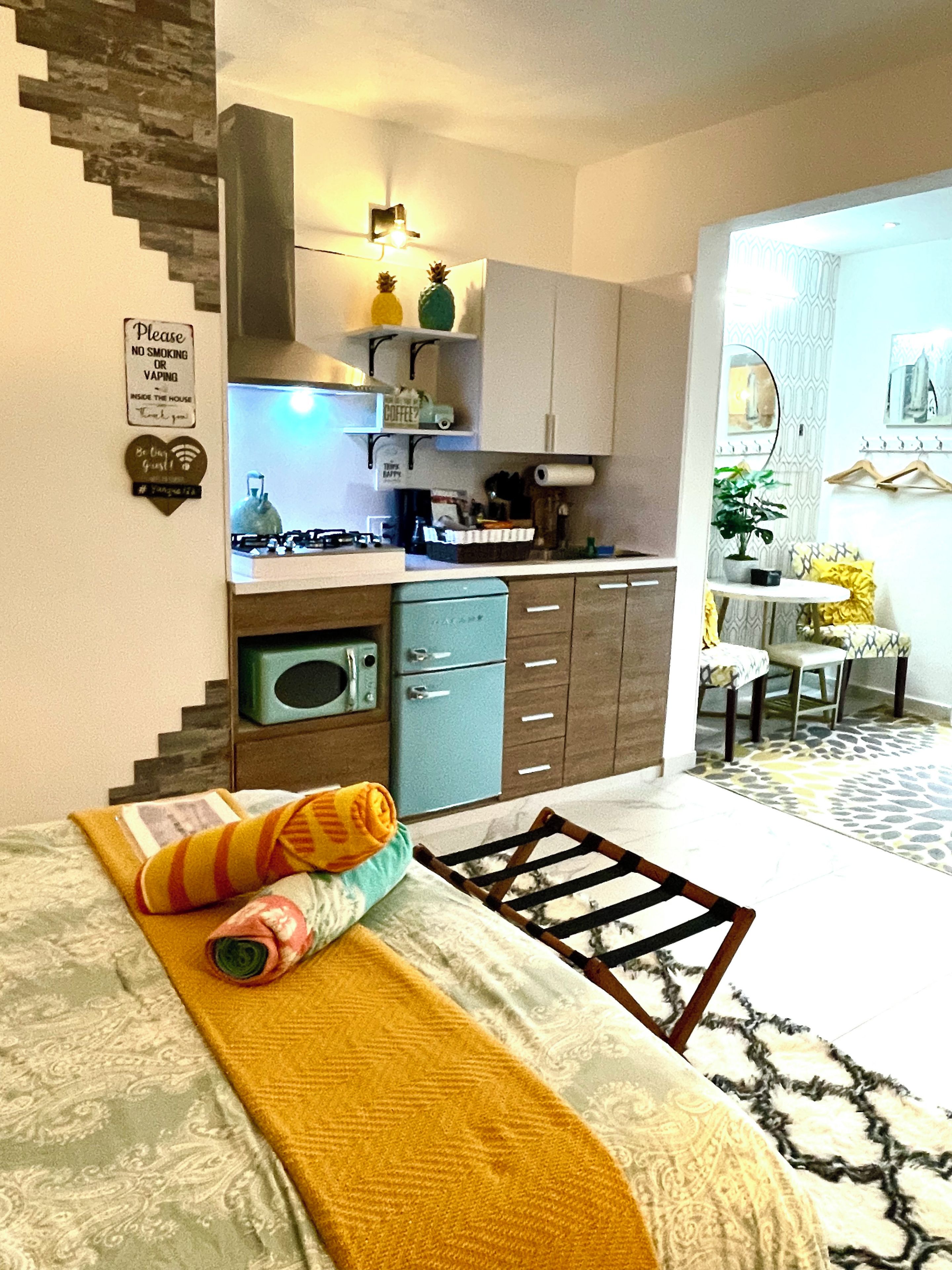 A compact living space with a kitchenette, a dining area, and a bed with a rolled-up towel and a blanket.