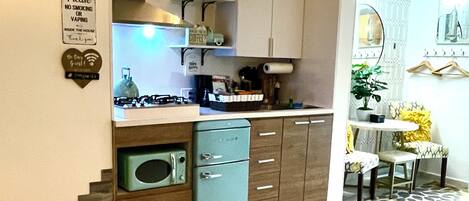 A compact living space with a kitchenette, a dining area, and a bed with a rolled-up towel and a blanket.