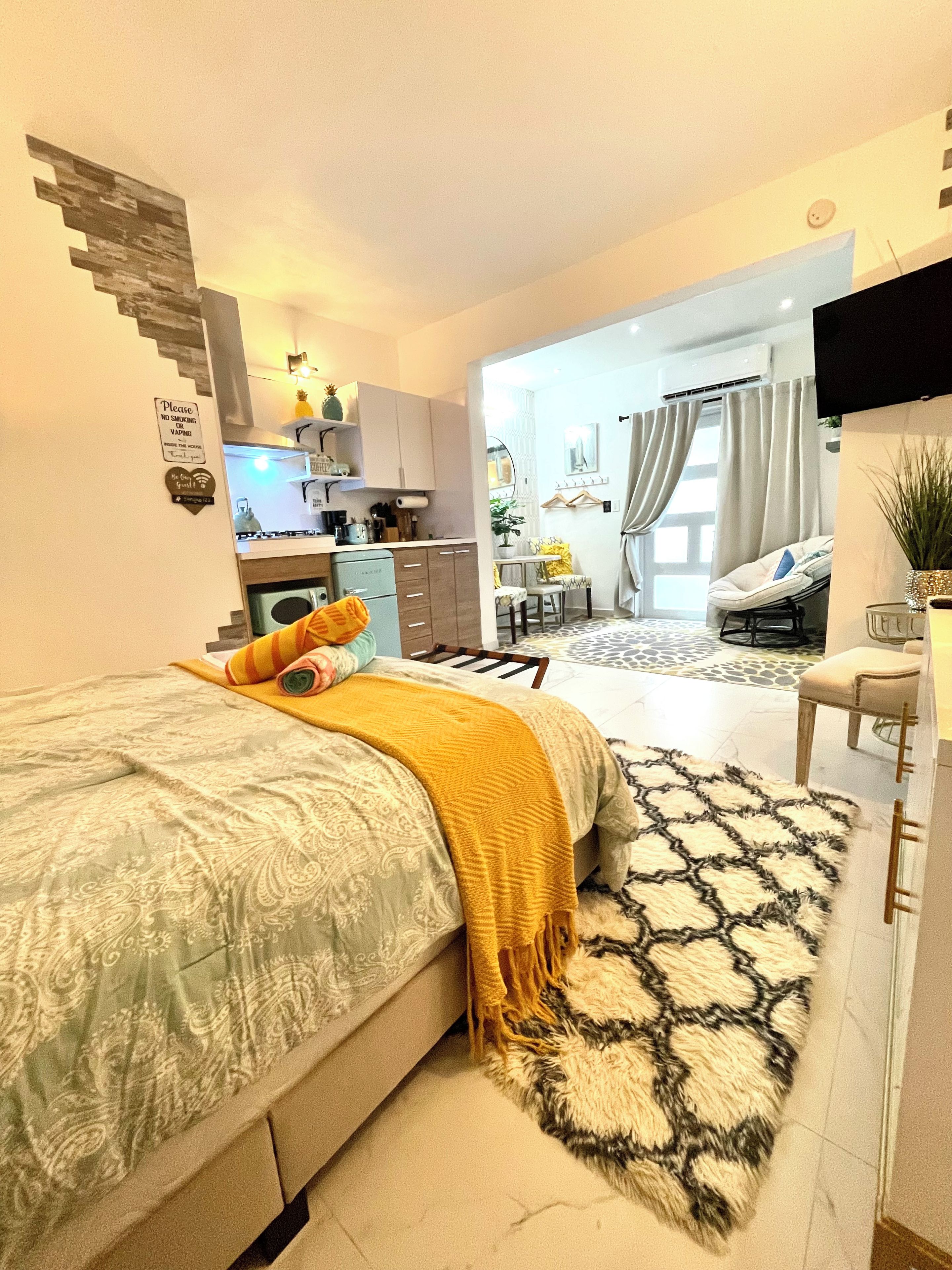 Un dormitorio moderno con cama, un escritorio pequeño y una zona de estar con sofá y mesa de comedor.